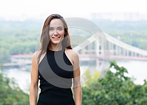 Young pretty likable cheerful woman posing summer city outdoor in Kyiv, Ukraine. Beautiful self-confident girl with long brown