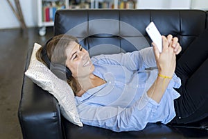 Young pretty long hair woman lying on a sofa making selfie on he