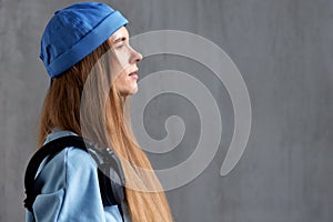 A young pretty long-haired girl in a blue sweater and a funny hat with black DJ headphones on her shoulder. Music, fun