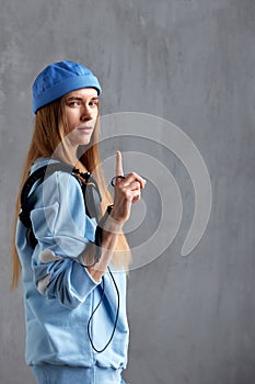 A young pretty long-haired girl in a blue sweater and a funny hat with black DJ headphones on her shoulder. Music, fun