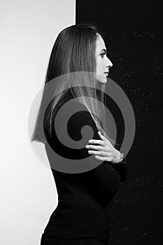 Young pretty longhaired woman dressed in black clothes on black and white background. Studio shot