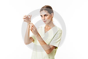 Young pretty nurse in uniform thoughtfully holding syringe in hands over white background isolated