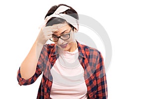 Young pretty pin-up girl wearing glasses showing headache gesture.