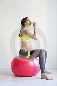 Young pretty pregnant woman sitting on fitness ball
