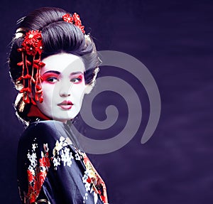 young pretty real geisha in kimono with sakura and decoration on black background