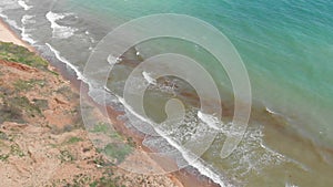 Young pretty redhead woman lay on the edge of clay cliff above the sea coastline