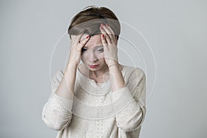 Young pretty and sad red hair woman looking worried and depressed crying and suffering headache and migraine pain and depression