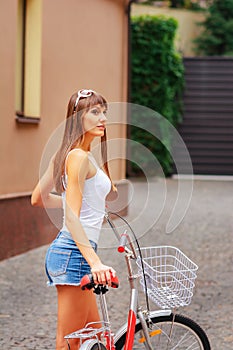 Young pretty sexy woman retro hipster style outdoor portrait with with red bicycle has fun and smiling