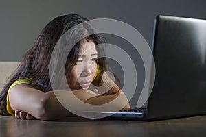 Young pretty shocked and surprised Asian Korean woman looking stressed at laptop computer feeling amazed and scared in cyber bully