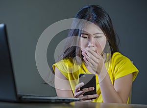 Young pretty shocked and surprised Asian Korean woman looking stressed at mobile phone feeling worried and scared in cyber bullyin