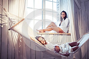 Young pretty sisters at home early morning in hammock, lifestyle casual people concept