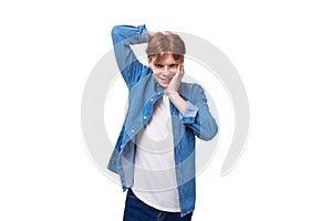 young pretty slender caucasian red-haired man in a denim shirt on a white background with copy space