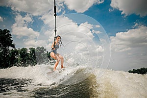 The ladys wakeboard is towed behind a motorboat by rope