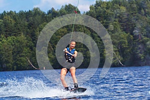 Young pretty slim brunette woman riding wakeboard on wave of mot