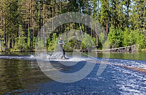 Young pretty slim brunette woman in wetsuit riding wakeboard on