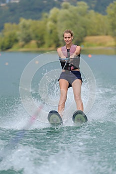 Young pretty slim woman riding wakeboard in lake