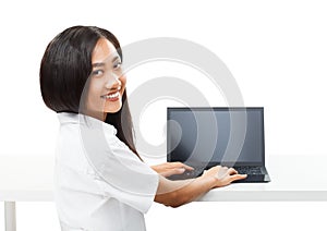 Young pretty smiling Asian woman typing on black laptop isolated