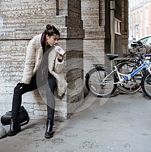 Young pretty stylish teenage girl outside on city street fancy fashion dressed drinking milk shake