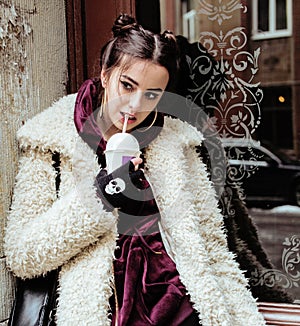 Young pretty stylish teenage girl outside on city street fancy fashion dressed drinking milk shake
