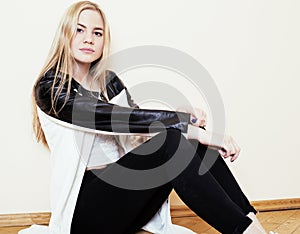 Young pretty teenage blond girl sitting on floor at home despair