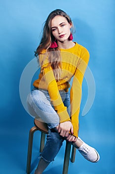 Young pretty teenage modern hipster girl posing emotional happy on blue background, lifestyle people concept