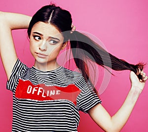 Young pretty teenage woman emotional posing on pink background, fashion lifestyle people concept