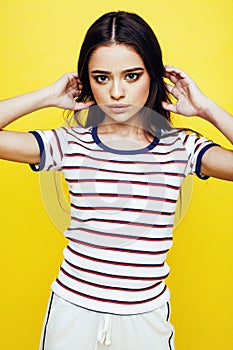 Young pretty teenage woman emotional posing on yellow background, fashion lifestyle people concept