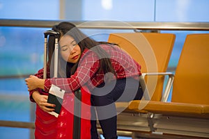 Young pretty tired and exhausted Asian Korean tourist woman in airport sleeping bored sitting at boarding gate hall waiting for de