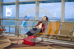 Young pretty tired and exhausted Asian Korean tourist woman in airport sleeping bored sitting at boarding gate hall waiting for de