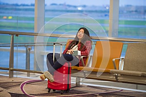 Young pretty tired and exhausted Asian Korean tourist woman in airport sleeping bored sitting at boarding gate hall waiting for de