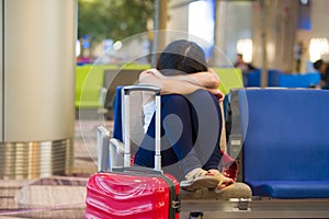 Young pretty tired and exhausted Asian Korean tourist woman in airport sleeping bored sitting at boarding gate hall waiting for de
