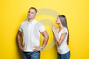 Young pretty woman apologizes to a man on the yellow background