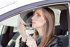 Young pretty woman apply makeup in car