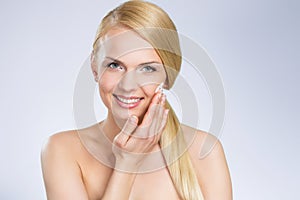 Young pretty woman applying cream on face
