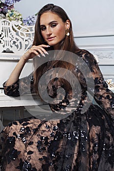 Young pretty woman in black lace fashion style dress posing in rich interior of royal hotel room, luxury lifestyle