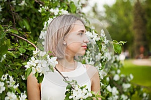 Young pretty woman with blonde bob haircut outdoor. Healthy girl in flowers garden portrait