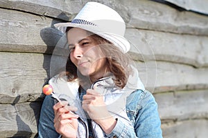 Young pretty woman with Chupa Chups on summer warm day. Beautiful girl in hat and jeans jacket with sweet lollipop