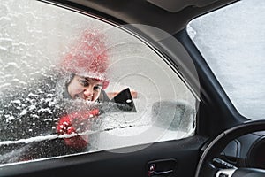 young pretty woman cleaning car after snow storm