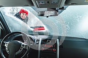 young pretty woman cleaning car after snow storm