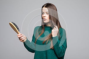 Young pretty woman comb her hairs wearing in green sweater isolated on gray background