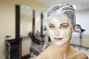 Young pretty woman in cosmetic mask and hat smiles photo