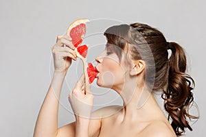 Young pretty woman or cute girl with long hair holds grapefruit fruit slice