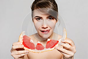 Young pretty woman or cute girl with long hair holds grapefruit fruit slice
