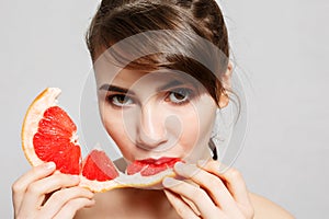 Young pretty woman or cute girl with long hair holds grapefruit fruit slice