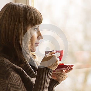 Young Pretty Woman Drinking Coffee near Window in Cafe
