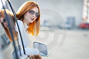 Young pretty woman driver in sunglasses looking out the car front window on a sunny summer day