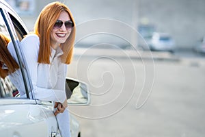 Young pretty woman driver in sunglasses looking out the car front window on a sunny summer day