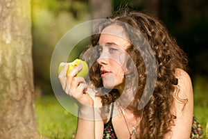 Young pretty woman eating apple on a field