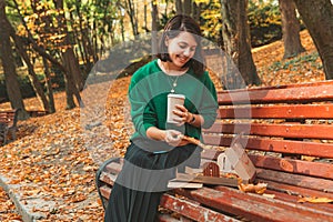 young pretty woman eating pizza drinking coffee outdoors at public park bench