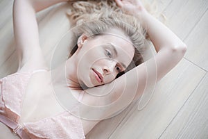 Young pretty woman in gentle lingerie lying on the floor. Beauty close up portrait of female face with natural skin, no makeup.